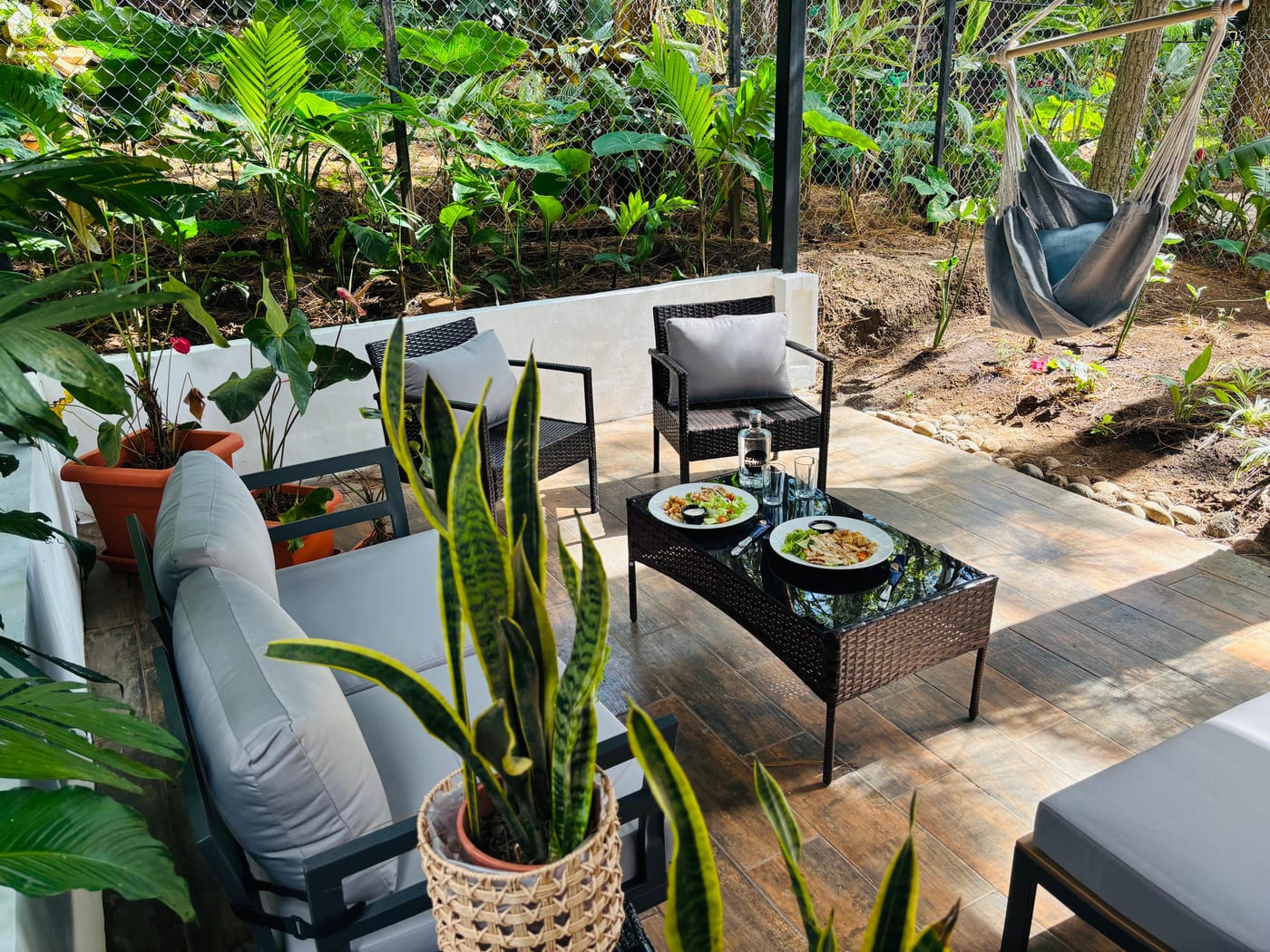 Private terrace of an Umbra cabin with lounge seating, a hanging chair and tropical garden